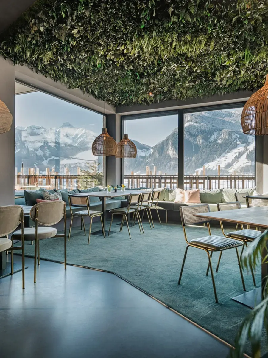 Lounge mit begrünter Decke aus Grünpflanzen und Blick auf verschneite Berge